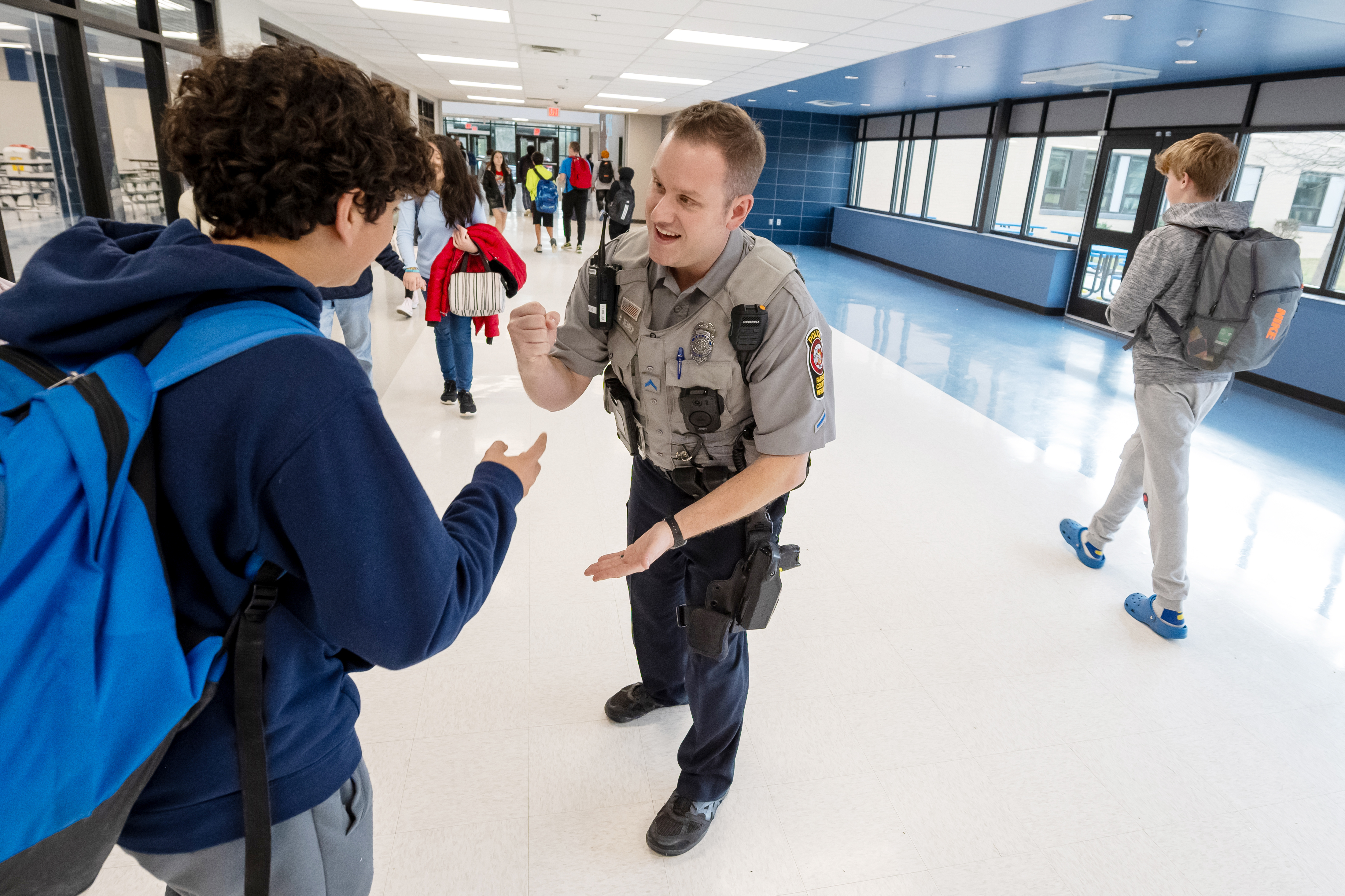 An officer plays rock paper scissors with a student